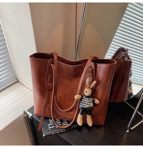 Detail of vintage brown PU leather tote with text print and cute bunny doll pendant