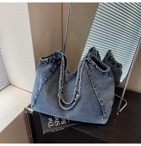 Detail view of washed denim tote bag with metal chain strap and retro textures