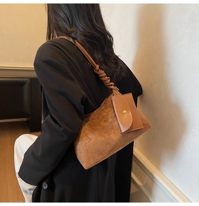 Dettaglio della borsa tote in pelle scamosciata marrone con manico annodato e borsellino