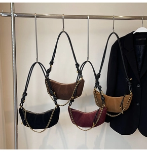 Detail of four matte suede crescent bags in black, brown, and burgundy with gold chains