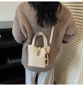 Détail du tissage du sac seau blanc avec breloque perlée et fermoir argenté