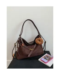 Detail of dark brown suede tote bag featuring gold hardware and a cute donut plush charm