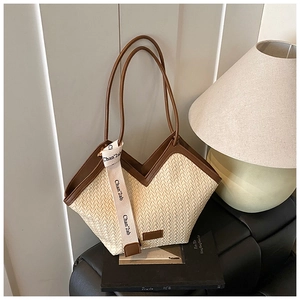 Detail of woven straw tote bag with brown leather trim and modern lettered ribbon