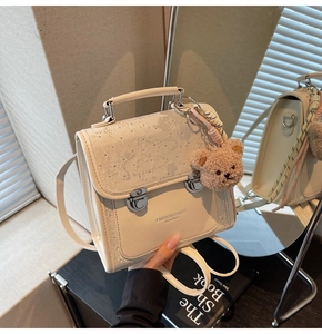 Detail of cream white PU leather backpack with embossed flap and brown teddy bear charm