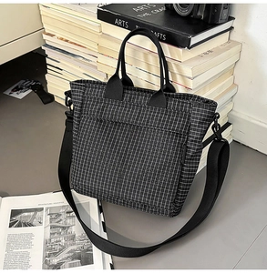 Detail of checkered tote bag with wide nylon strap and exterior pocket on art books