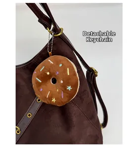 Plush chocolate donut charm with colorful embroidery on a brown suede tote bag