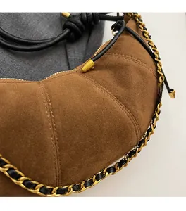 Detail of vintage brown suede dumpling bag with stitching and woven chain strap