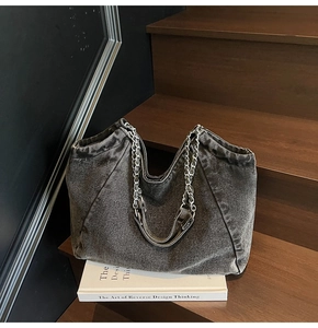 Close-up of vintage grey denim tote bag showing metal chain strap and fabric texture
