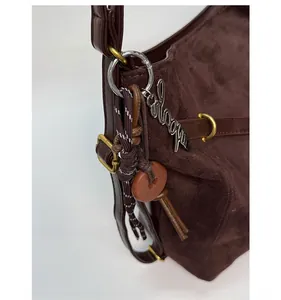 Detail of dark brown suede shoulder bag with vintage copper hardware and metallic logo