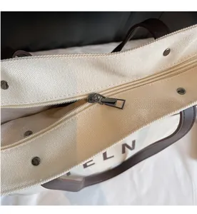 Detailed close-up of the smooth metal zipper and leather trim on this canvas tote bag