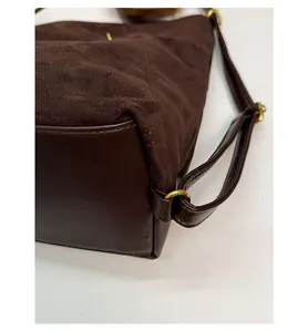 Detailed close-up of dark brown suede shoulder bag showing reinforced leather base structure