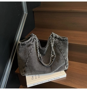 Detailed close-up of washed denim tote bag with silver chain straps on vintage steps