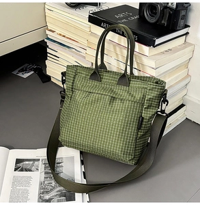 Detail of green plaid tote bag with wide shoulder strap next to vintage camera and books