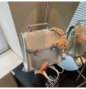 Detail of silver metallic backpack with mini bear pendant and striped scarf accessory
