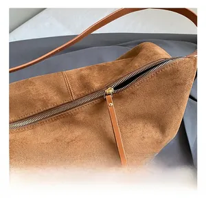 Detailed close-up of premium gold metal zipper and suede texture on brown tote bag