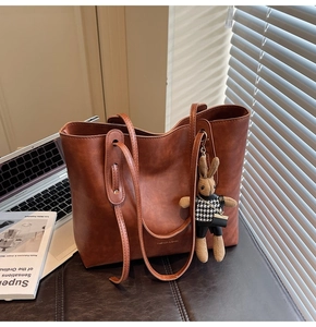 Close-up of brown vintage tote bag with fashion embossing and cute rabbit pendant