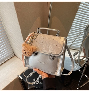 Silver metallic backpack with plush bear charm and Fashion & Bags Leather inscription