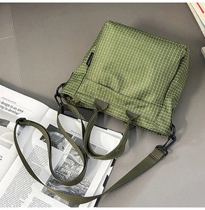 Detail of green checkered tote bag with durable nylon texture and adjustable strap