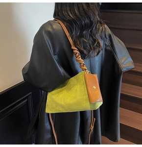 Close-up of green suede tote bag featuring brown woven strap and a leather mini pouch