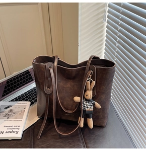 Macro shot of dark brown retro leather tote bag with a cute rabbit doll charm
