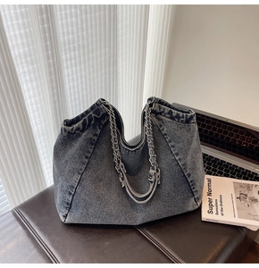 Detail of vintage denim tote bag with silver metal chain strap on leather seat