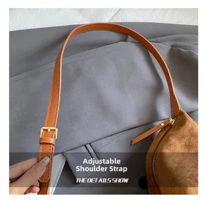 Detail of adjustable leather shoulder strap and gold buckle on a brown suede tote bag