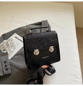 Close-up of black leather bag with lace texture, silver rivets and fashion lettering