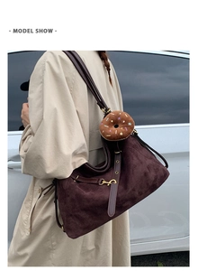 Detail of dark brown suede tote bag featuring a colorful donut plush charm on side strap