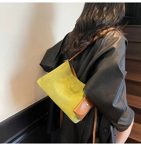 Detail of green suede tote bag with brown leather pouch and adjustable strap on a model