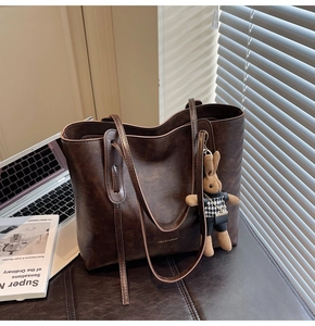 Detail of vintage brown tote bag with leather texture and cute bunny plush charm
