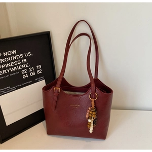 Detail of burgundy PU leather tote bag with vintage beaded charm and golden hardware