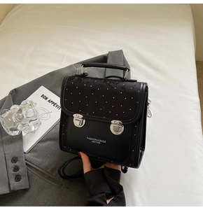 Detail of black polka dot flap and dual silver locks on a structured fashion handbag