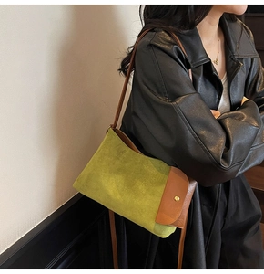 Close-up of green suede shoulder bag with brown leather trim and metal clasp details
