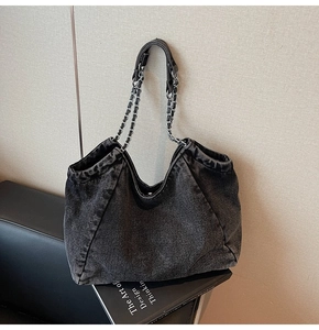 Detail view of the dark grey denim tote bag with metal chain and leather shoulder strap
