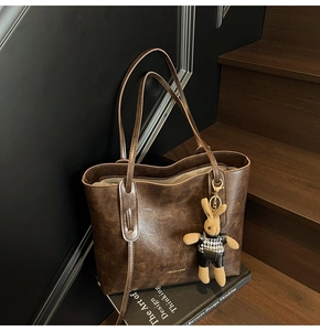 Detail of vintage dark brown faux leather tote bag with cute rabbit pendant on books