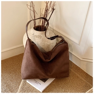 Détail d'un sac cabas en daim marron vintage avec fermeture éclair sur des livres