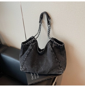 Detail of premium washed denim tote bag with silver chain straps and fabric texture