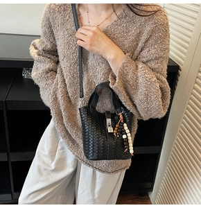 Détail du sac seau noir tressé avec cadenas métallique et charm en perles colorées