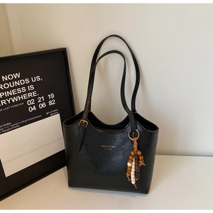 Detail of black faux leather tote bag with vintage texture and wooden bead charm