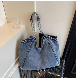 Detail shot of the large capacity denim tote bag with silver chain strap on luggage