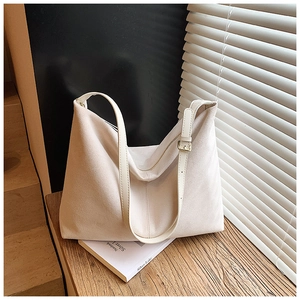 Détail d'un grand sac fourre-tout en daim beige avec bandoulière sur bois naturel
