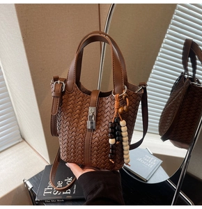 Détail du sac seau tressé marron foncé avec boucle métallique et pendentif en perles