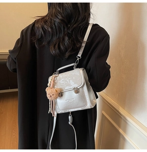 Silver glitter backpack with marble texture and bear charm worn on a black coat