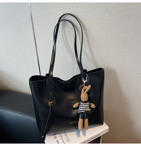 Detail of black faux leather tote with 'FASHION & BAGS' text and a cute rabbit charm