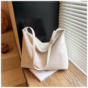Détail de boucle dorée ajustable et texture daim doux sur un sac cabas beige élégant