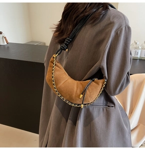 Detailed back view of brown suede crescent bag with gold chain and black leather strap