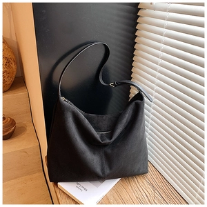 Vue détaillée du grand sac cabas en daim noir avec fermeture éclair sur une table en bois