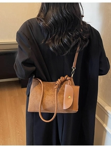 Brown suede hobo bag with knotted strap and matching pouch shown on a model
