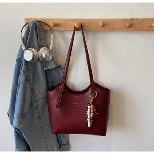 Detail view of burgundy tote bag with gold buckle and bohemian wooden bead accessory