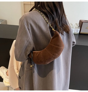 Detailed view of the brown frosted leather crescent bag with gold chain strap on model